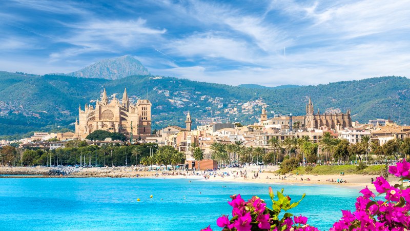 Palma de Mallorca Palma by med fjell i bakgrunnen og klart, turkis hav foran