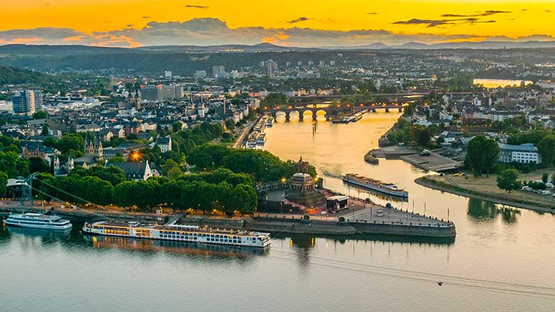 Mtepunktet der Mosel og Rhinen mtes. Flere elvecruisebter ligger ved kai p kveldstid. 