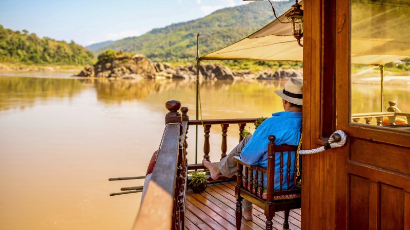 en mann som skuer utover elven mens skipet seiler avsted