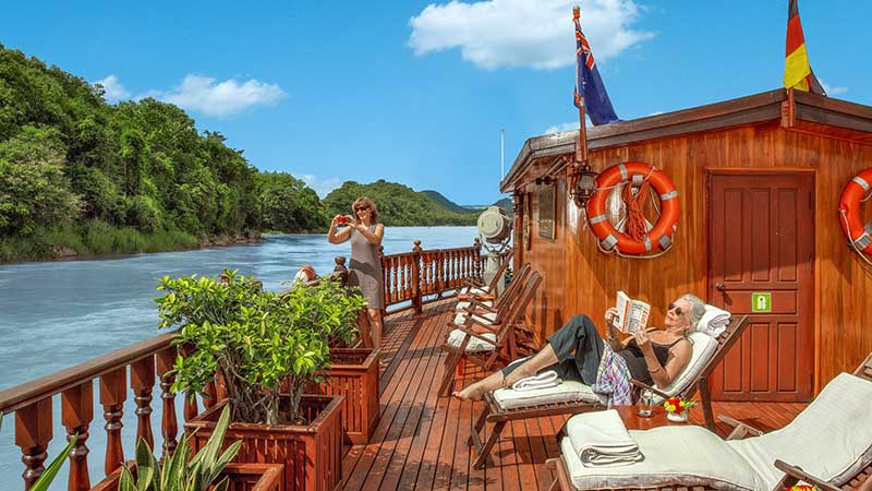 en dame som ligger og soler seg i solstolen og en annen som tar bilder