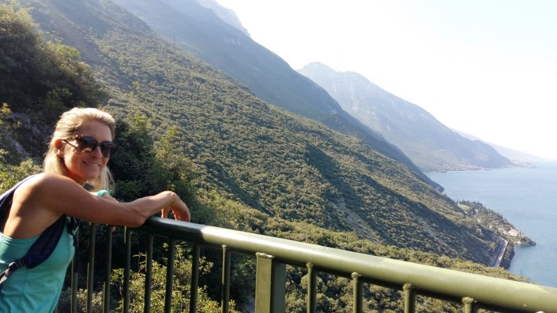 Panoramastien ovenfor Torbole en person lener seg over et rekkverk og ser utover en innsjø