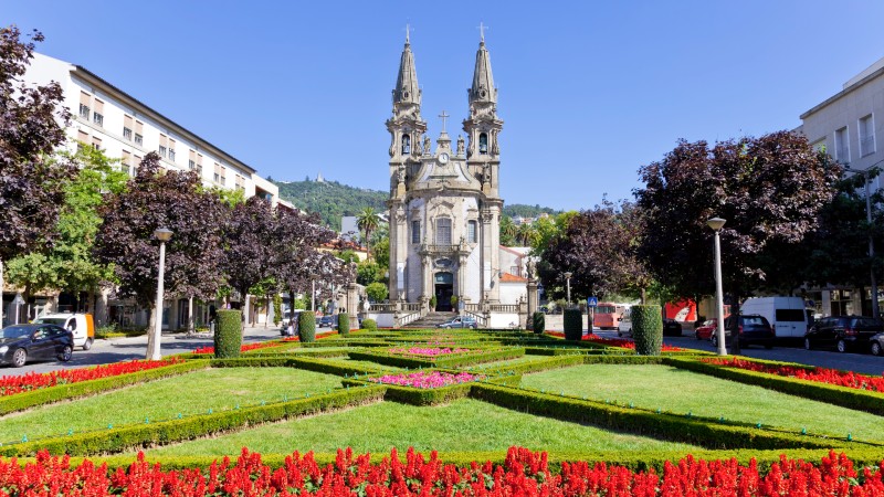 Kirken Sao Gualter i Guimarães med grønt gress og røde blomster i forgrunnen