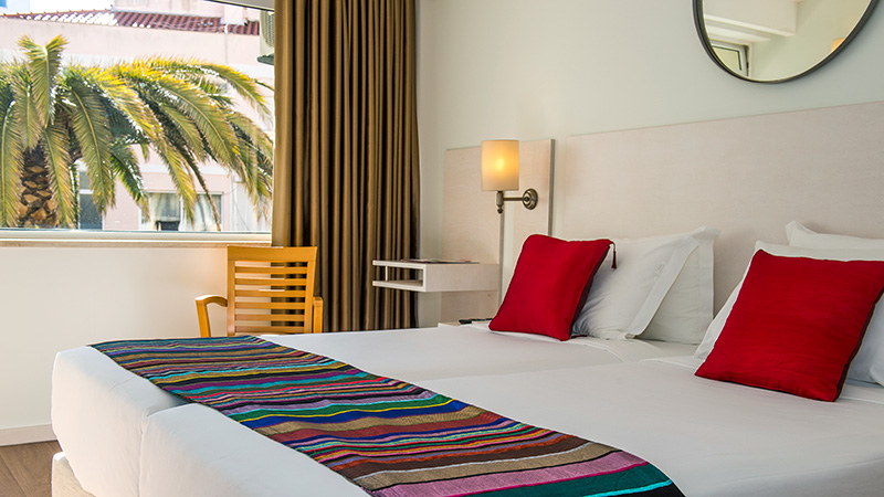 Twin senger på hotellrom med utsikt mot palme. 
