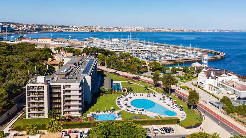 Stort hotell ved havet med en btmarina i bakgrunnen