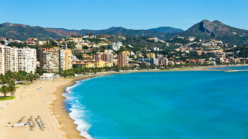 Strand i forkant av sentrum av Malaga. Fjell i bakgrunnen.