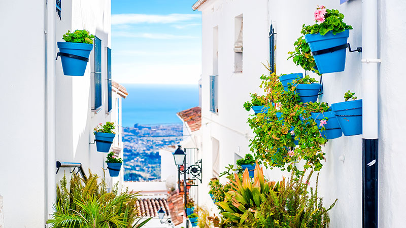 Trang gate med blomster i Mijas. Utsikt mot havet.